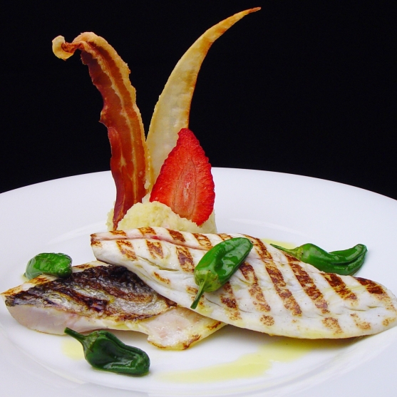 Grilled sea bass with crispy pieces and padrón peppers